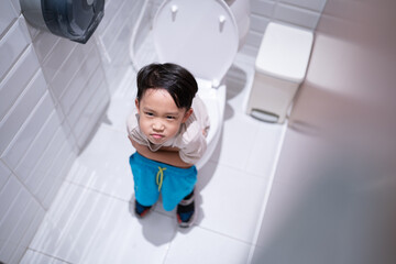 Fototapeta na wymiar A boy is sitting on toilet with suffering.