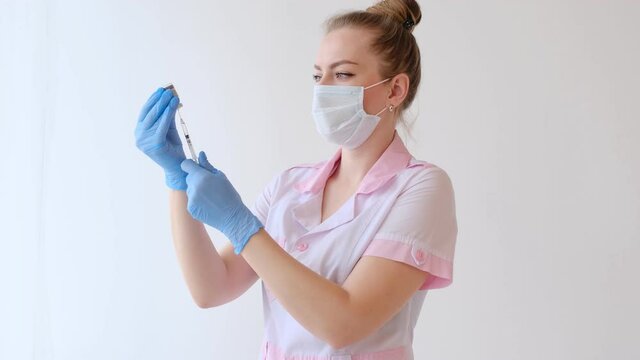 Female Doctor in pink uniform and protective mask filling syringe with medication. concept of Vaccination and immunization. injection medicine.