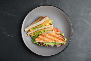 Plate with tasty sandwiches on black table, top view