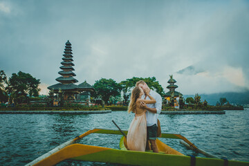 Happy young couple spending time at the ulun datu bratan temple in Bali, cruising on a catamaran