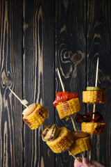 Human hand holder vegetables grille (corn, onion, sweet pepper and zucchini) on skewers. Copy space.