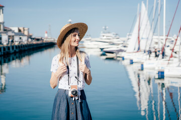 Young beautiful healthy woman walks in the harbor on the background of the yacht mooring.