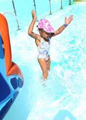 Little сaucasian girl in a cap and swimsuit plays in the pool on vacation. Children's entertainment at sea. Vacation with children. Summer concept.