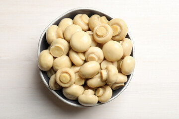 Delicious marinated mushrooms in bowl on white wooden table, top view