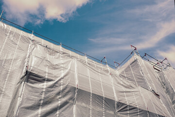 Building under construction with scaffolding and protective net is cover building for safety and...