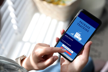 Woman tracking parcel via smartphone indoors, closeup