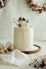 Closeup shot of delicious Boho ombre cake with dry flowers on a white table © Edgard Schmeichel/Wirestock