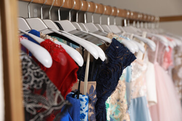 Different beautiful dresses on hangers in rental clothing salon