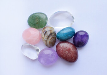 Tumbled gems of various colors. Amethyst, rose quartz, agate, apatite, aventurine, rock crystal on white background.