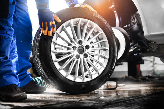 Auto mechanic working in garage and changing wheel alloy tire.