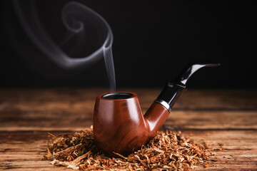 Smoking pipe with tobacco on wooden table