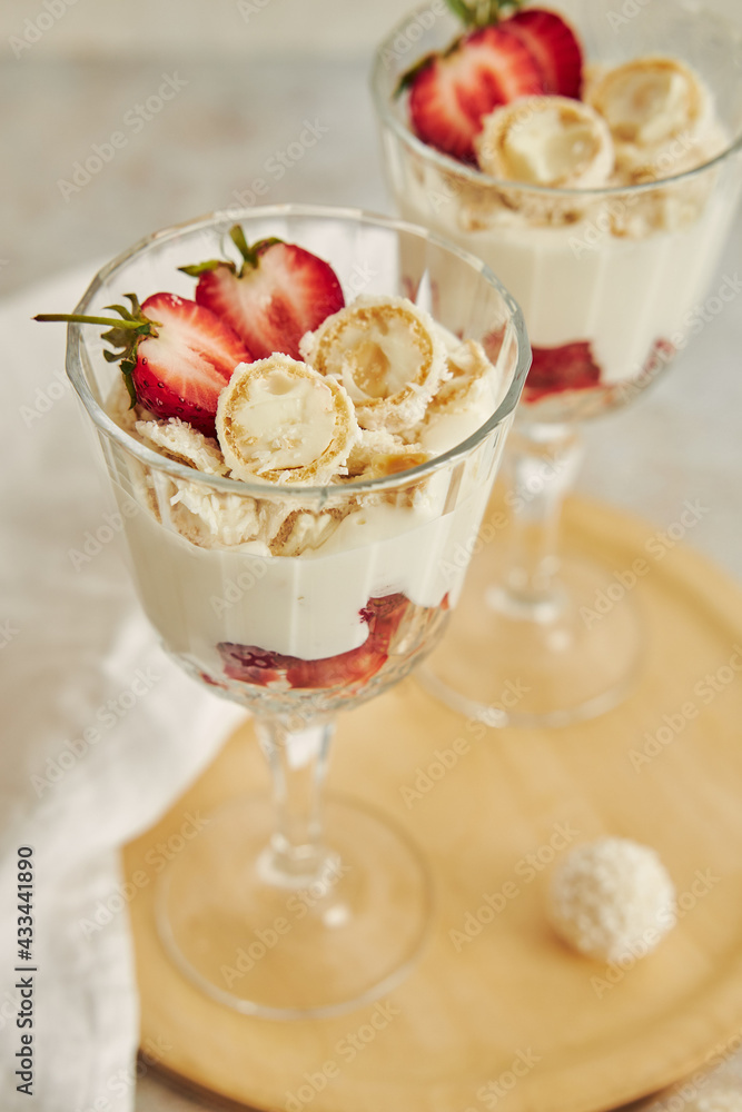 Sticker Delicious cream dessert with coconut truffles and strawberries on a wooden round serving board