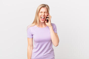 young blonde woman shouting aggressively, looking very angry and calling with a smart phone