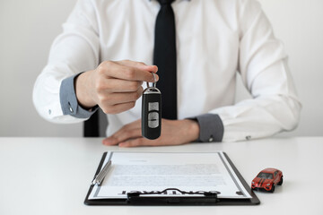 Auto sales agent holding a key in the office.