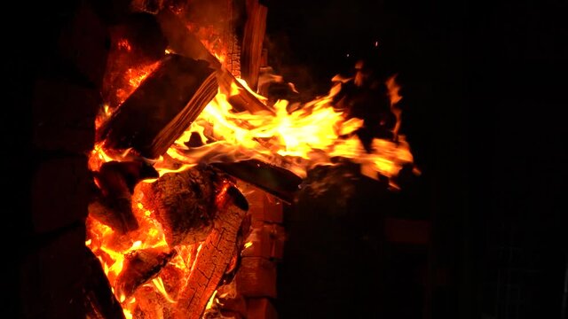 A large fire made of wood in a special place for a fire lined with bricks at night. Vertical Video. Slow motion