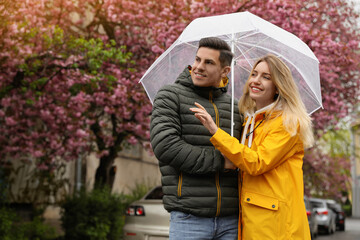 Lovely couple with umbrella walking on spring day