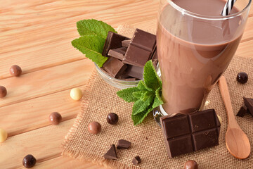 Glass with milk chocolate shake on wooden table elevated view