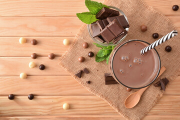 Glass with milk chocolate shake on wooden table top view