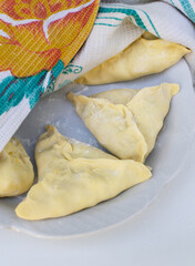 Raw sambus on a white plate. Vertical orientation.
