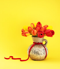 Beautiful flowers tulips in a concrete vase on a yellow background