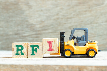 Toy forklift hold letter block I to complete word  RFI (Abbreviation of request for information) on wood background