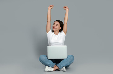 Young woman with modern laptop on grey background