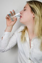 Portrait of a beautiful young blonde woman drinking a glass of water