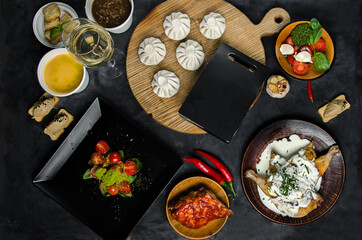 Various cuisines of the world on a wooden table. View directly above the table. Khinkali, ribs, chicken with sauce, salads and pate.