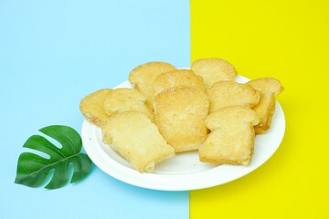 Crispy garlic bread on white plate on blue and yellow background