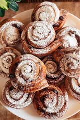Puff pastry cakes curl with powdered sugar on top. A close-up of a bakery product. Confectionery work and customer service. A treat on a tray.