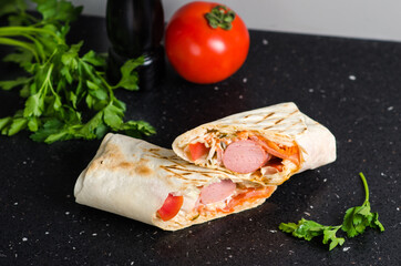 Juicy shawarma with sausages and vegetables. Concept: fast food. Black background with tomatoes, spices and herbs