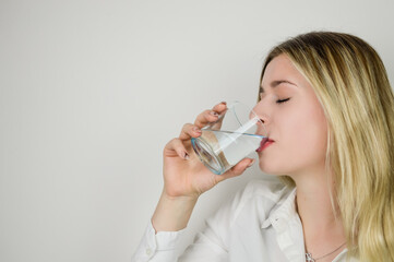 Portrait of a beautiful young blonde woman drinking a glass of water