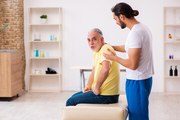 Obraz premium Old male patient visiting young male doctor chiropractor