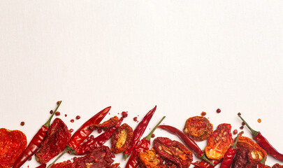 Peppers and tomatoes background. Dried hot chili peppers and red sun-dried tomatoes on a white plate. Spices and vegetables food minimal flat lay background concept