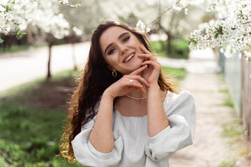 Lovely girl near blooming trees in the park. Outdoor walking in at sunny day. Lifestyle of young woman