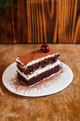 Close-up of a piece of chocolate cake with milk cream. The treat lies on disposable tableware. Takeaway food. Dessert in a cafe or restaurant.