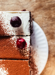 Close-up of a piece of chocolate cake with milk cream. The treat lies on disposable tableware. Takeaway food. Dessert in a cafe or restaurant.
