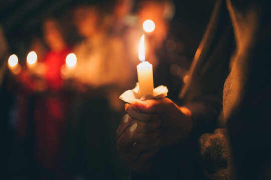 a girl holds a lighted candle in her hands, a religious tradition, a symbol of the Christian faith, a wax candle burns with an even flame, blow out a candle, a smoke from an extinguished wick