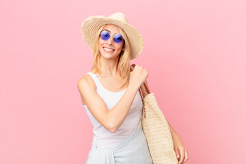 young blonde woman feeling happy and facing a challenge or celebrating. summer concept