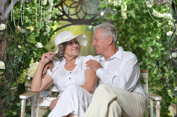 Fototapeta premium Elderly couple sitting on white wooden bench