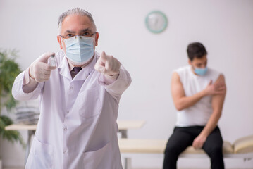 Young male patient visiting old male doctor in vaccination conce