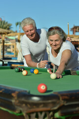 smiling senior couple playing billiard together