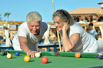 smiling senior couple playing billiard together