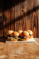 Mini burger on a stand close-up. Children fast food in a restaurant or cafe. Macro photo of burger ingredients with meat and vegetables. Eco burgers for children