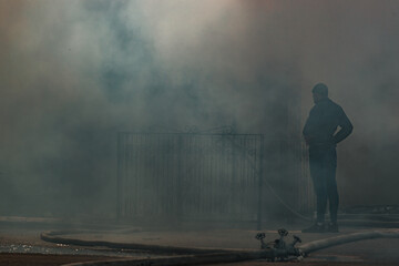 the fire destroys the building. the fire brigade pours water on the burning house. people are...