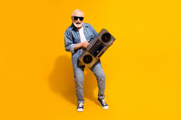 Naklejka premium Full body photo of positive carefree man hands hold boombox toothy smile isolated on yellow color background