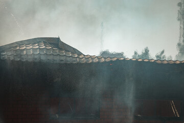 the fire destroys the building. the fire brigade pours water on the burning house. people are...