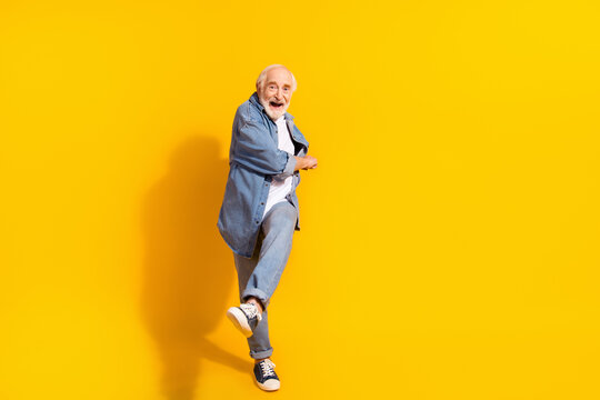 Full body photo of funky happy cheerful old man dance feel young good mood isolated on yellow color background