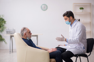 Obraz premium Old male patient visiting young male doctor otorhinolaryngologis