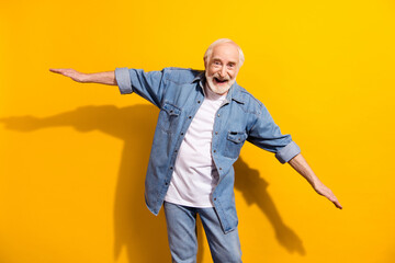 Portrait of attractive cheerful comic man having fun flying like plane isolated over vivid yellow color background
